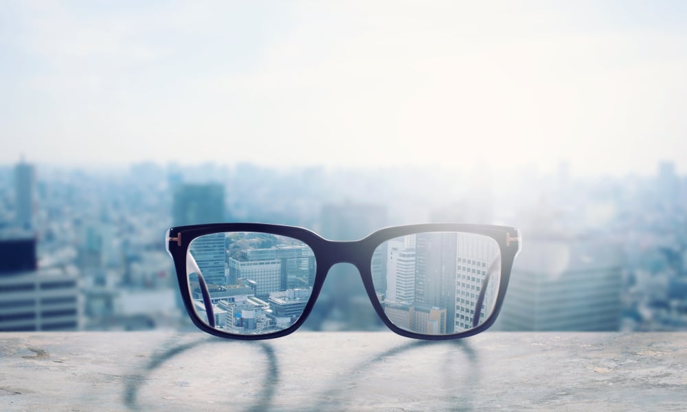 Correcting eyeglasses on a ledge of a skyscraper overlooking the city